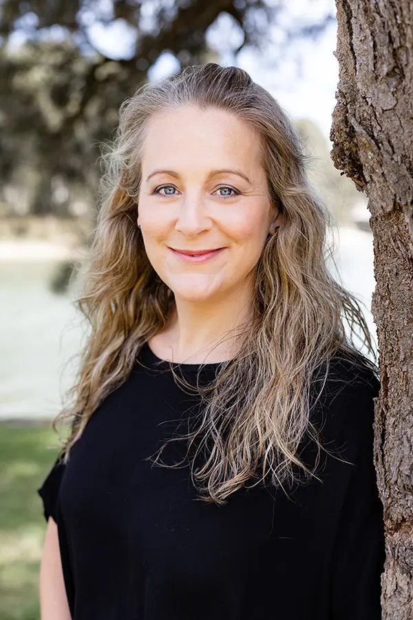 Zaneta Neucom smiling in a black shirt outdoors.