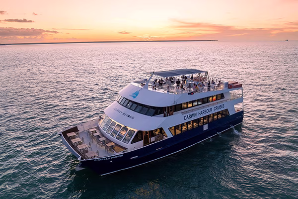 Cruise boat on water at sunset.